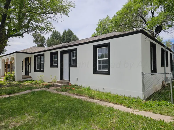 a backyard of a house with potted plants and large tree