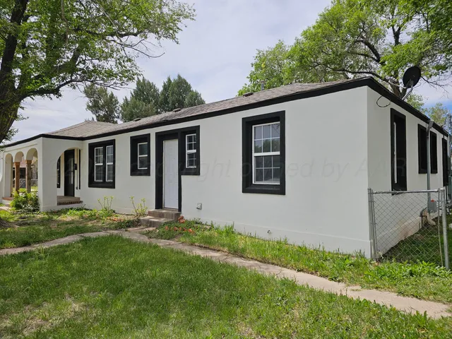 a backyard of a house with potted plants and large tree