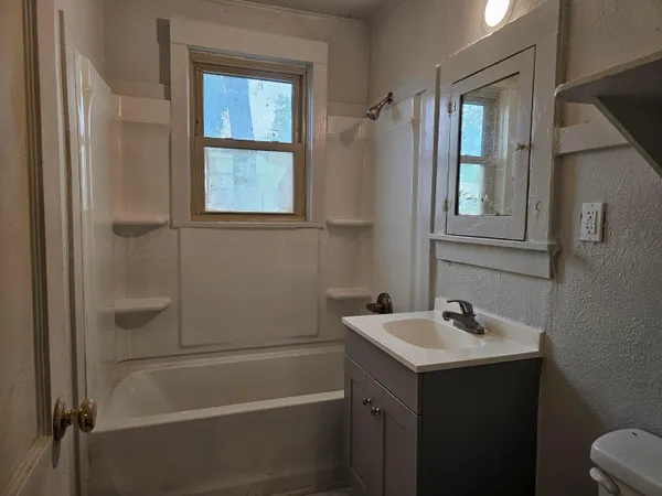 a bathroom with a bathtub sink vanity and mirror