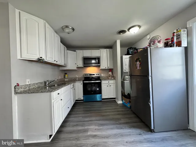 a kitchen with granite countertop a refrigerator stove top oven and cabinets