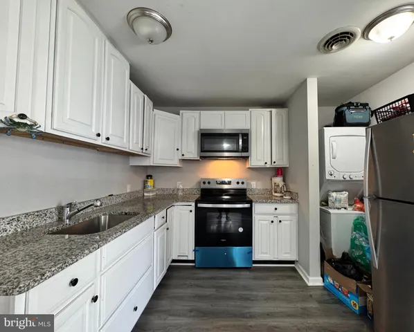 a kitchen with granite countertop a refrigerator a sink dishwasher a stove top oven a refrigerator and cabinets with wooden floor