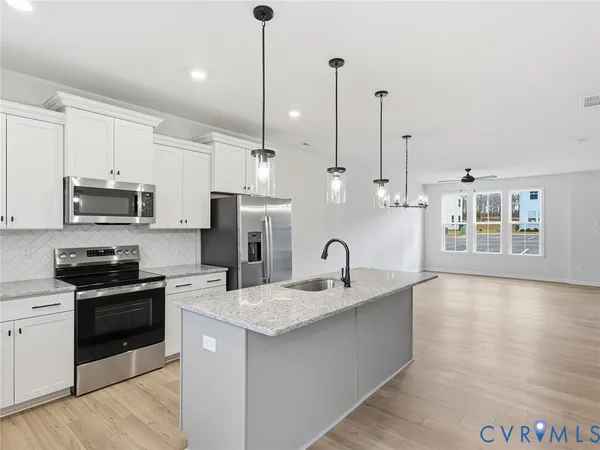 a kitchen with stainless steel appliances granite countertop a sink a stove and a wooden floor