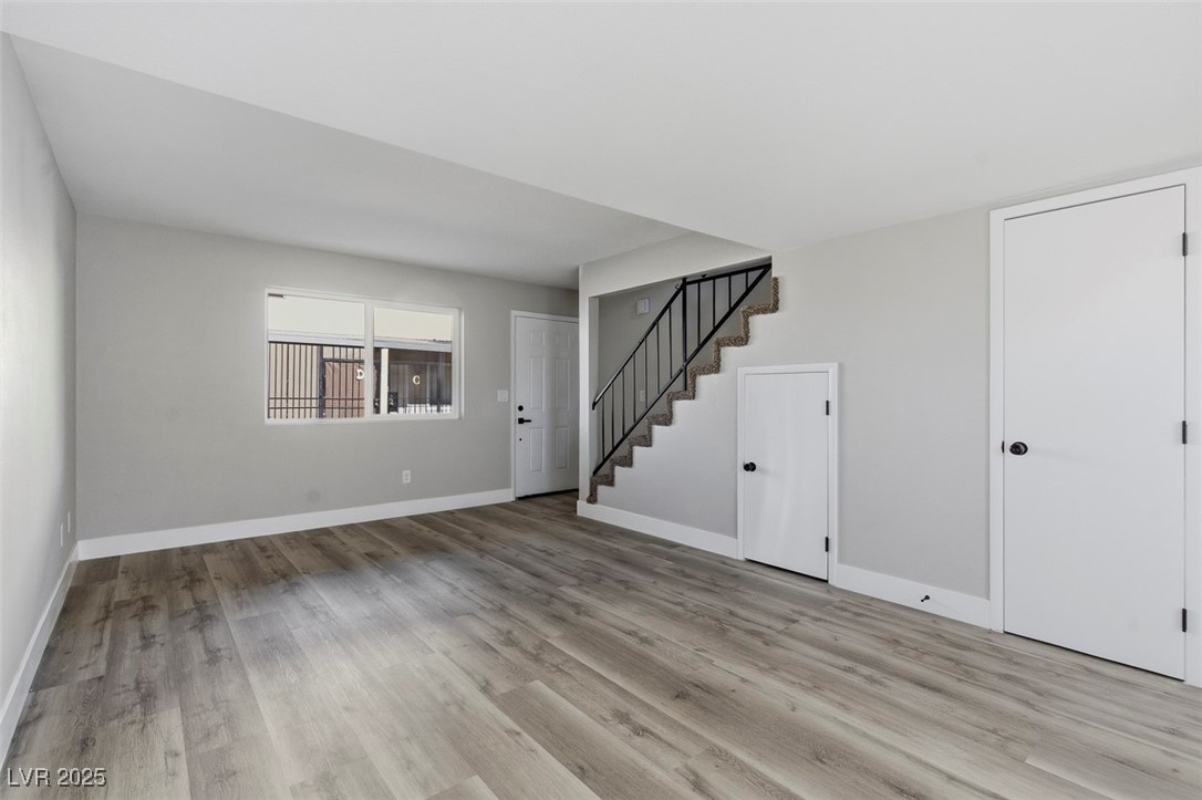 3517 Rio Robles Drive, Unit D North Las Vegas, NV 89030 - Photo 11 of 35 Unfurnished living room with light wood-style floors and stairway