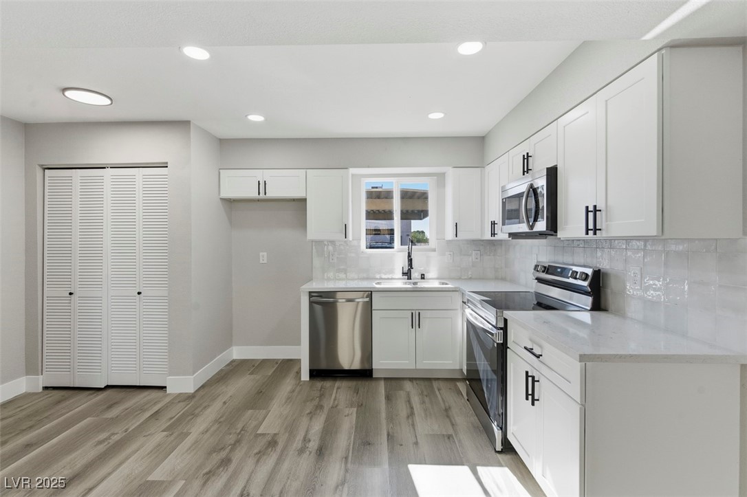 3517 Rio Robles Drive, Unit D North Las Vegas, NV 89030 - Photo 14 of 35 Kitchen featuring appliances with stainless steel finishes, white cabinetry, light stone countertops, recessed lighting, and light wood-style flooring