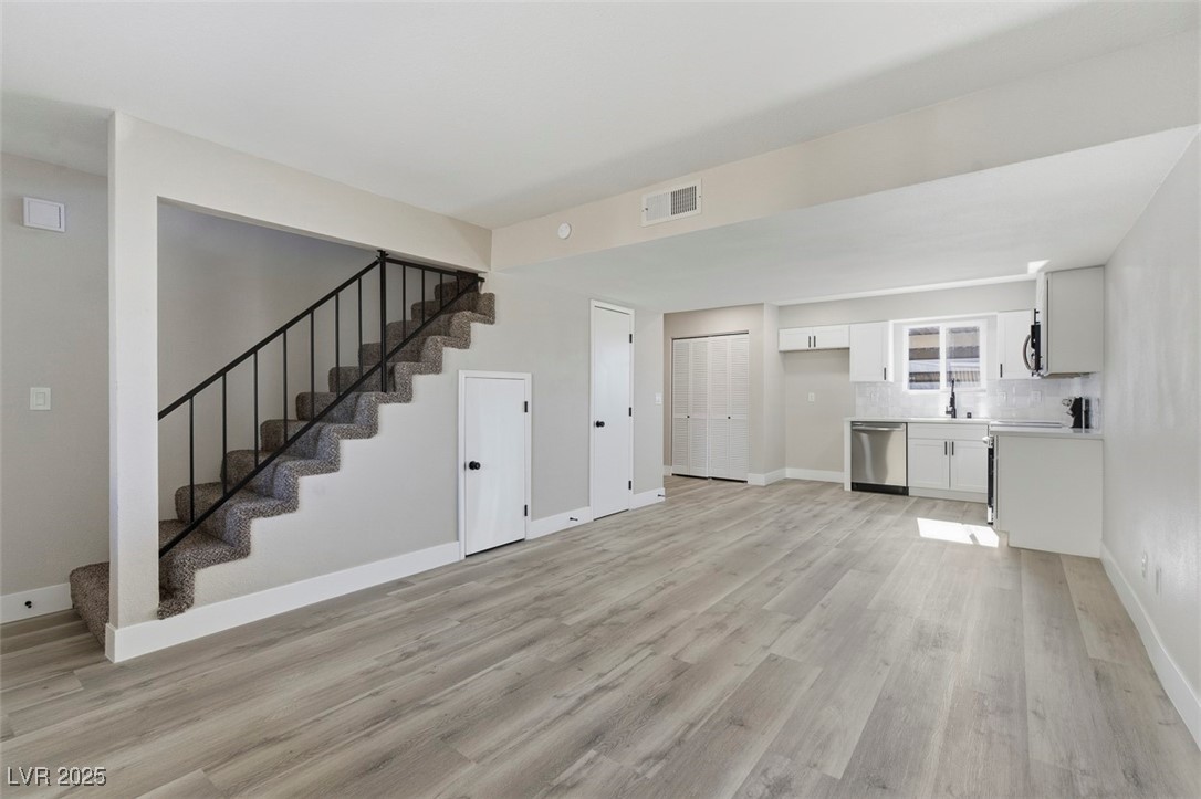 3517 Rio Robles Drive, Unit D North Las Vegas, NV 89030 - Photo 10 of 35 Unfurnished living room with stairway and light wood finished floors