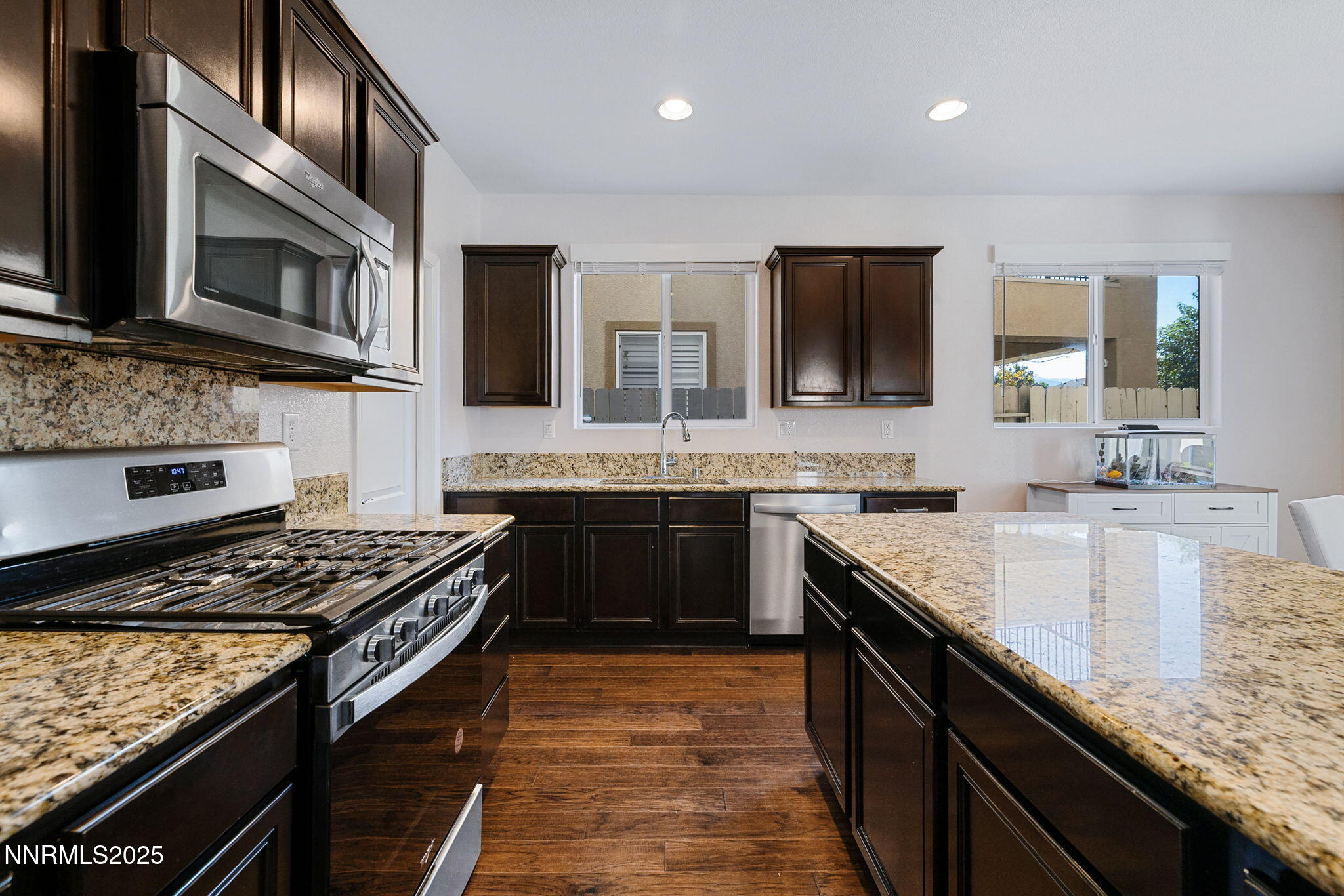 1876 Braemore Drive Reno, NV 89521 - Photo 4 of 34 a kitchen with stainless steel appliances granite countertop a stove top oven a sink dishwasher a microwave oven and a dining table with wooden floor