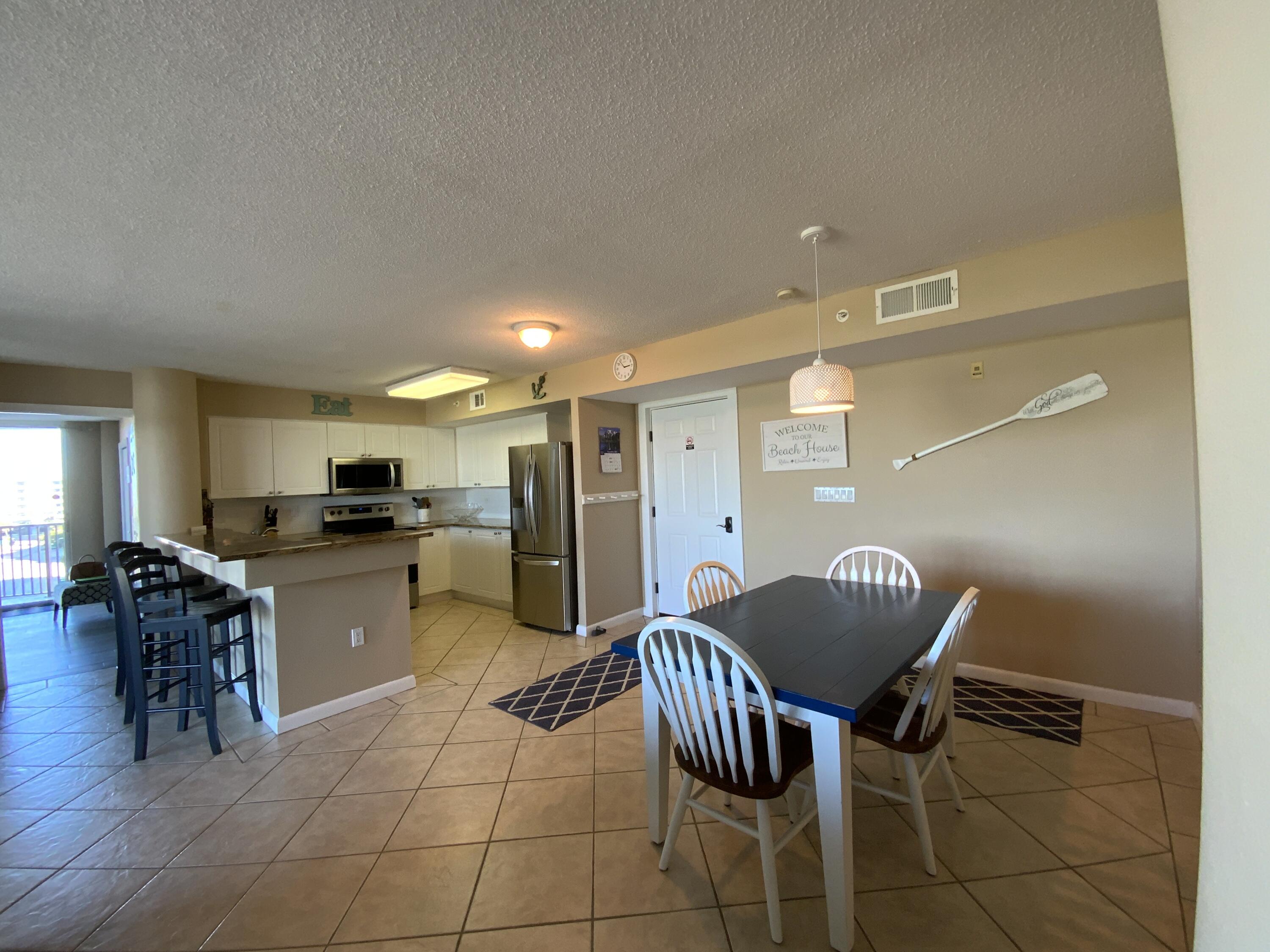 670 Santa Rosa Boulevard, Unit 503 Fort Walton Beach, FL 32548 - Photo 5 of 44 a kitchen with a dining table chairs and a refrigerator