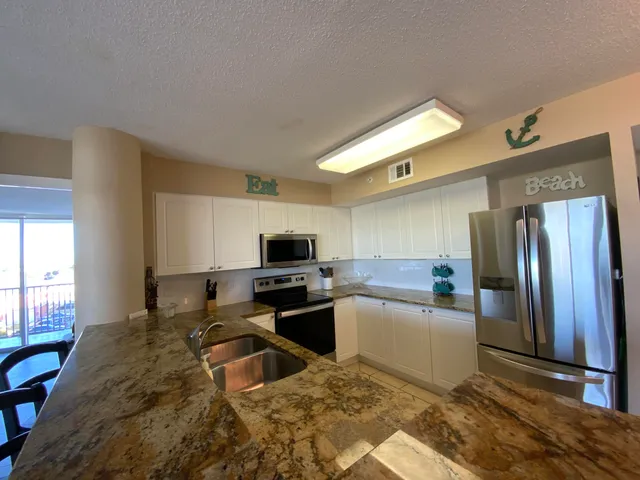a kitchen with granite countertop a refrigerator and a stove top oven