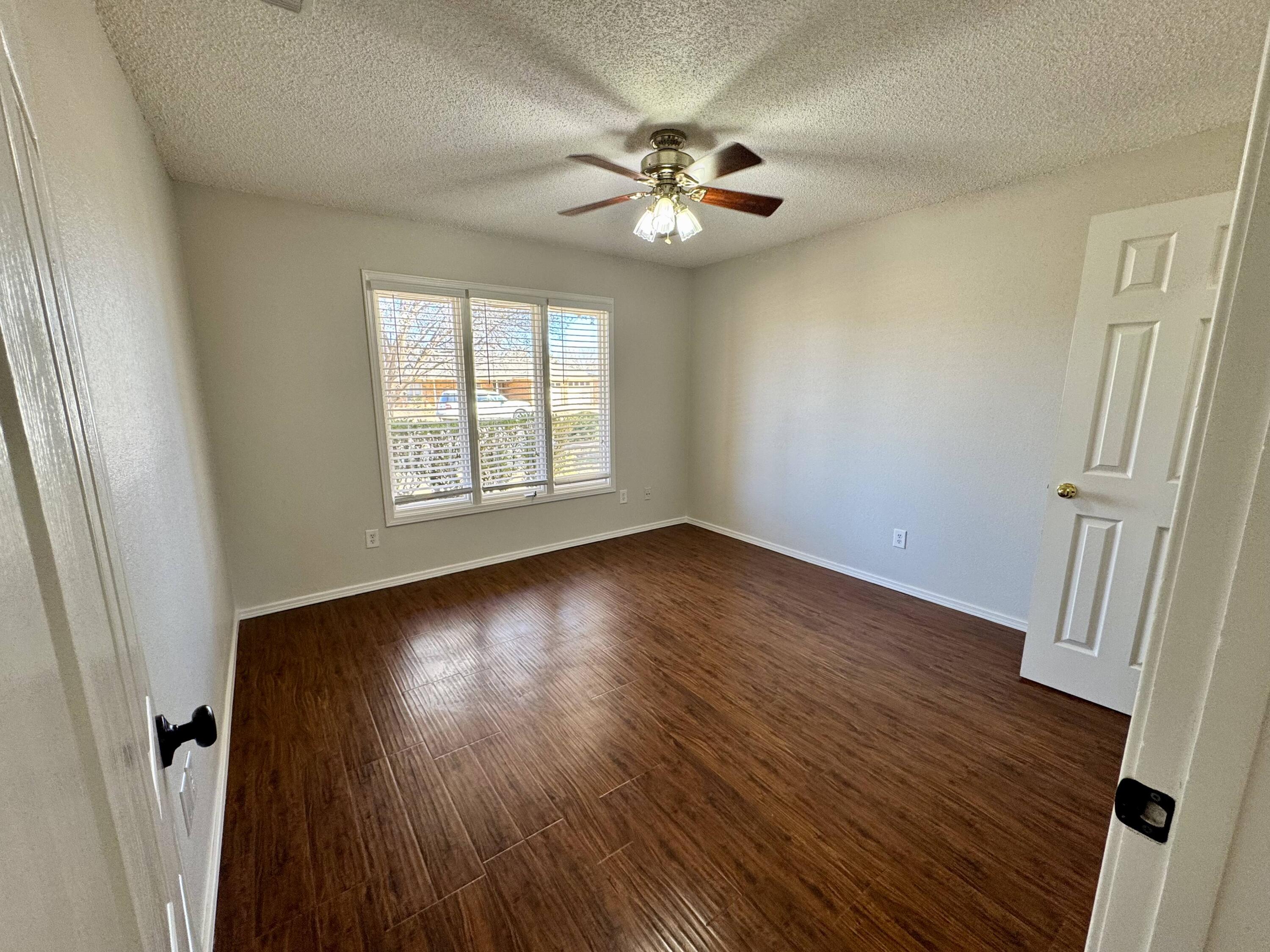 5421 94th Street Lubbock, TX 79424 - Photo 11 of 22 a view of an empty room with wooden floor and a window