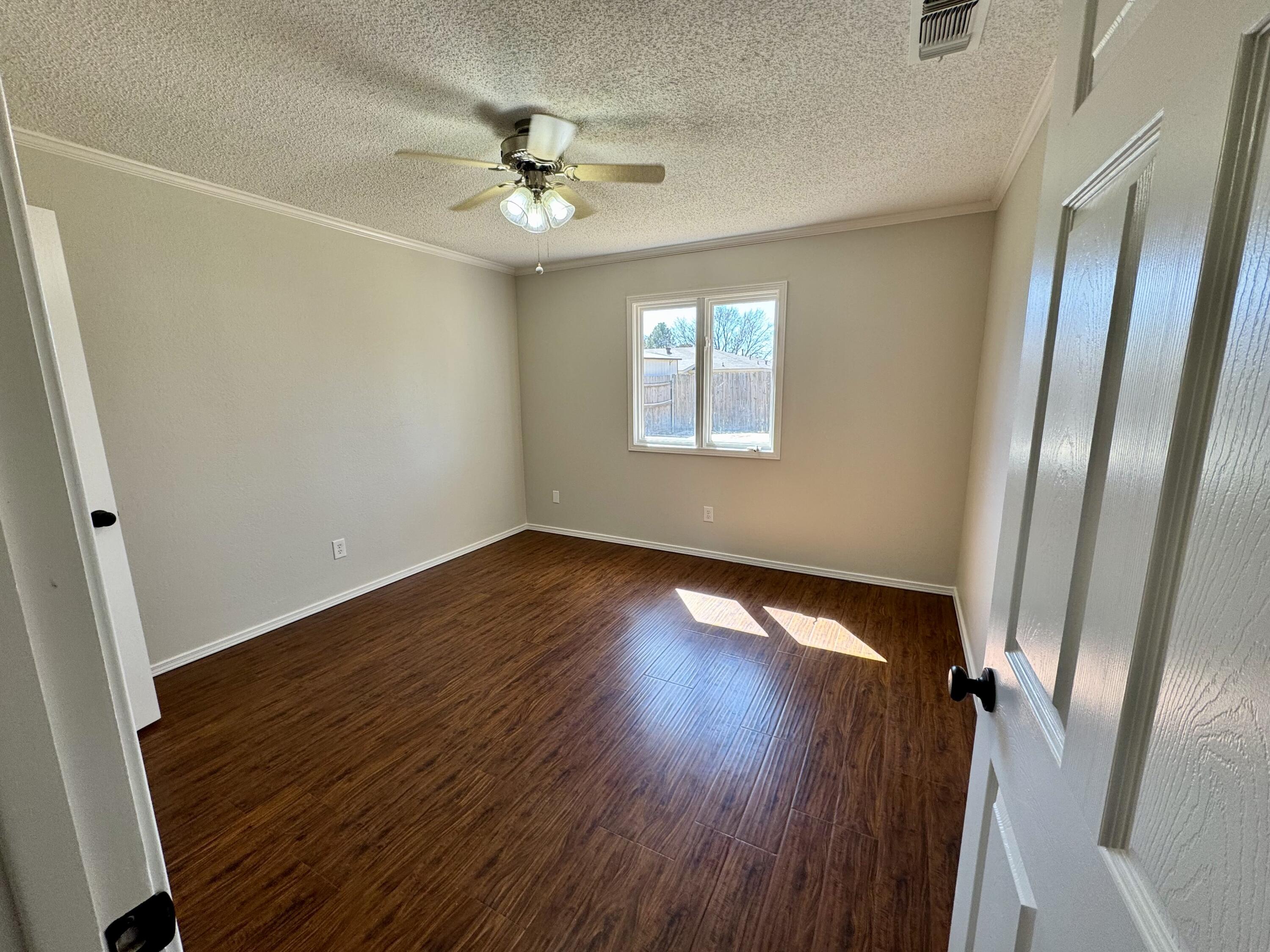 5421 94th Street Lubbock, TX 79424 - Photo 16 of 22 a view of an empty room with wooden floor and a window