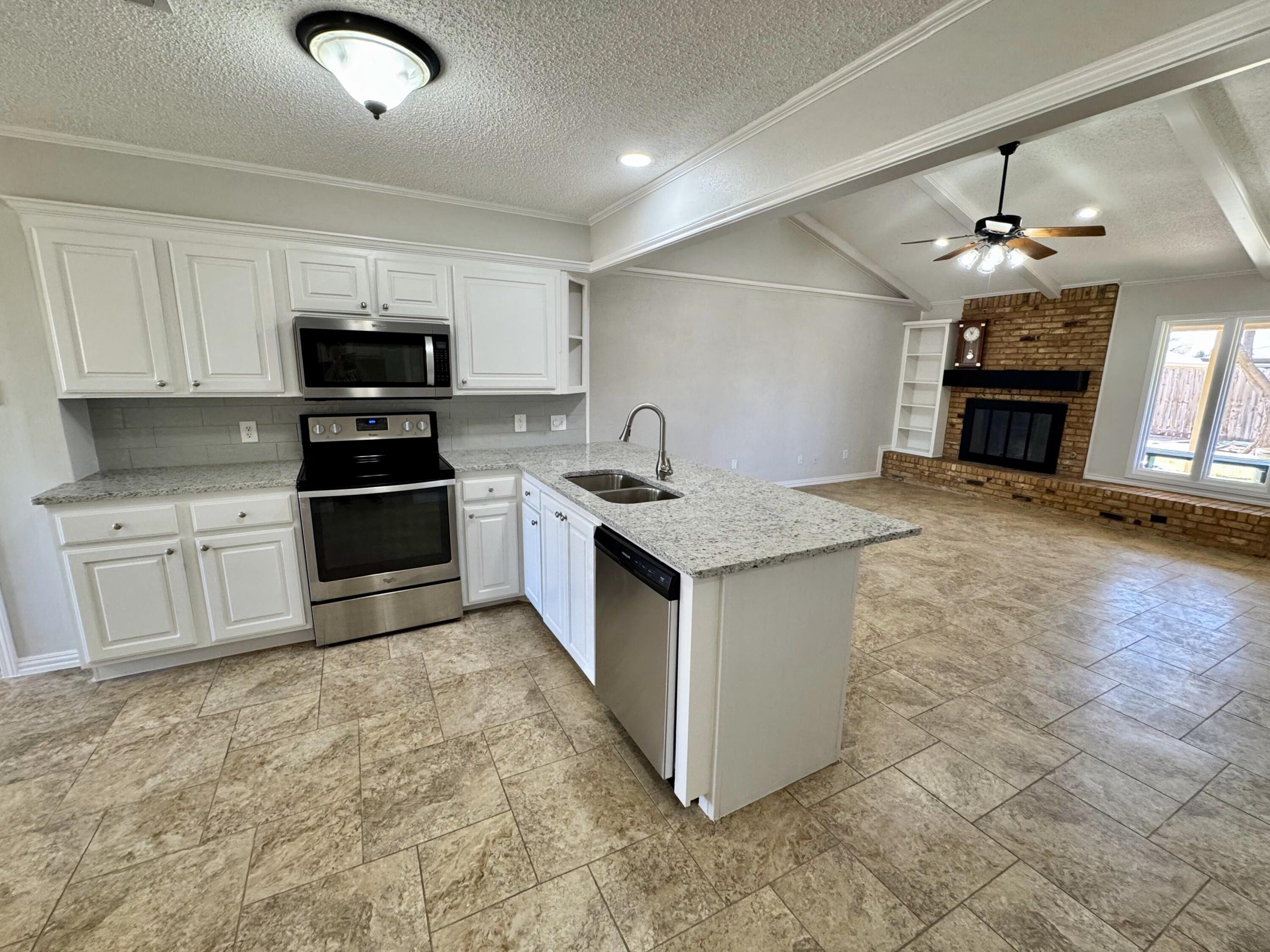 5421 94th Street Lubbock, TX 79424 - Photo 5 of 22 a kitchen with stainless steel appliances granite countertop a sink stove and refrigerator