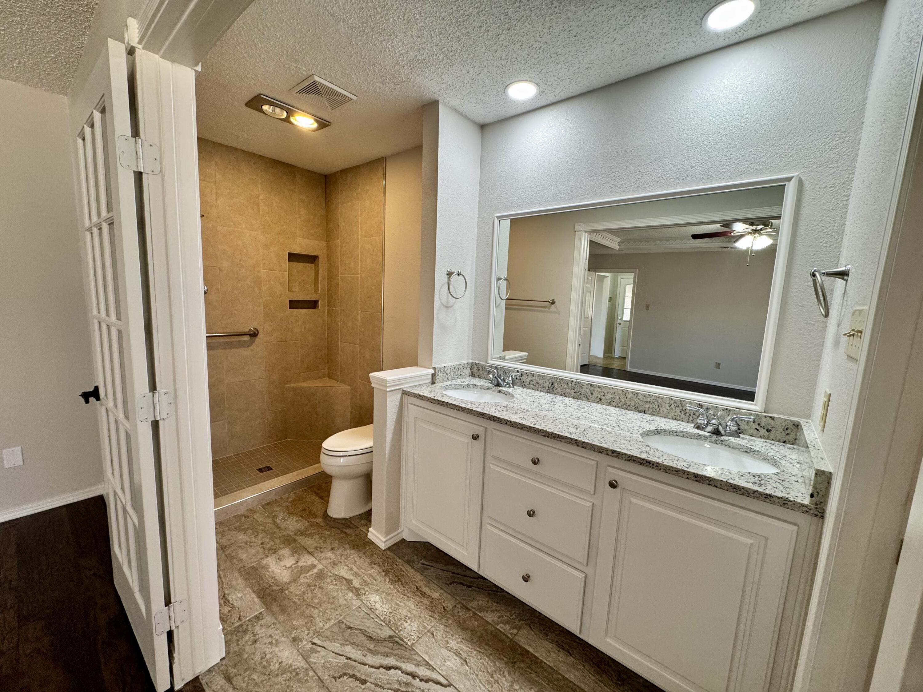 5421 94th Street Lubbock, TX 79424 - Photo 10 of 22 a bathroom with a granite countertop sink toilet and shower