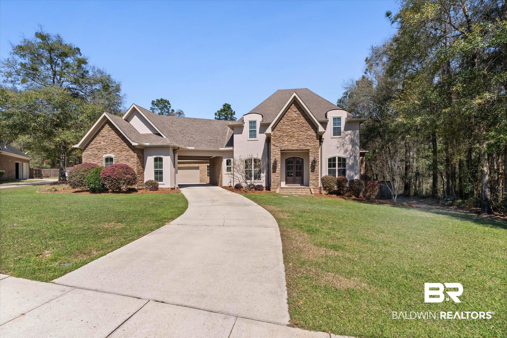 7676 Rockstone Lane Mobile, AL 36695 - Photo 42 of 47 French country style house featuring stone siding, a front yard, roof with shingles, driveway, and stucco siding