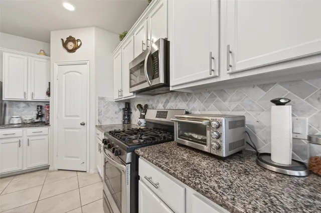 a kitchen with stainless steel appliances granite countertop a stove a sink and a white cabinets