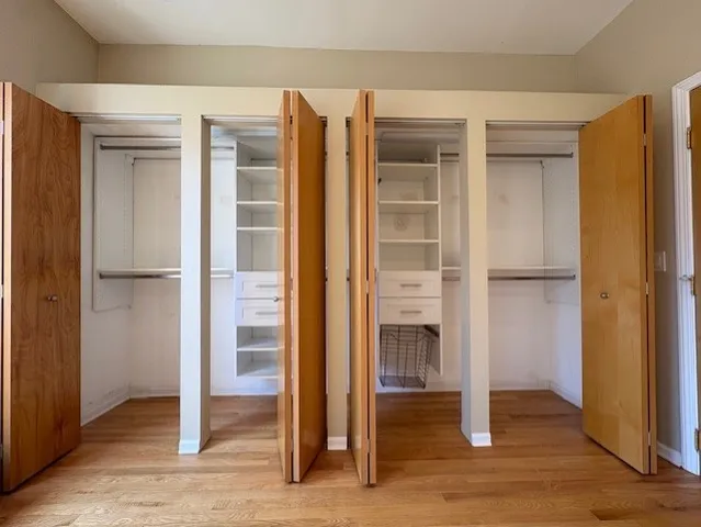 an empty room with wooden floor closet and windows
