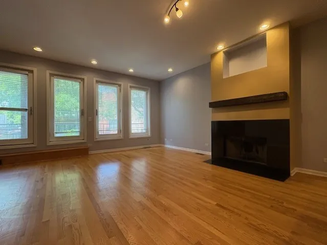an empty room with wooden floor fireplace and windows