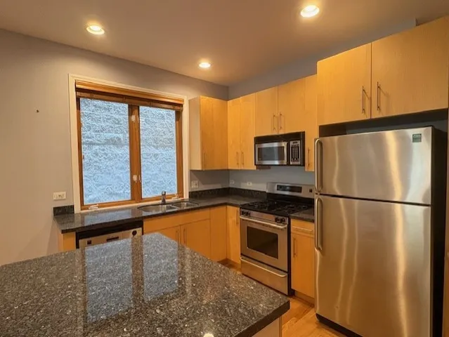 a kitchen with stainless steel appliances granite countertop a refrigerator a stove and a sink with wooden floor