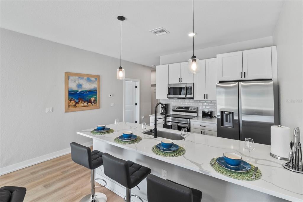 9155 Agate Street Port Charlotte, FL 33981 - Photo 2 of 30 a kitchen with stainless steel appliances granite countertop a dining table chairs and refrigerator