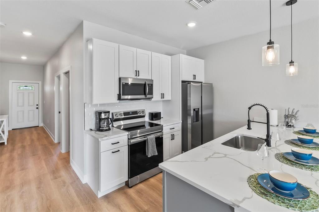 9155 Agate Street Port Charlotte, FL 33981 - Photo 24 of 30 a kitchen that has a lot of white cabinets and stainless steel appliances