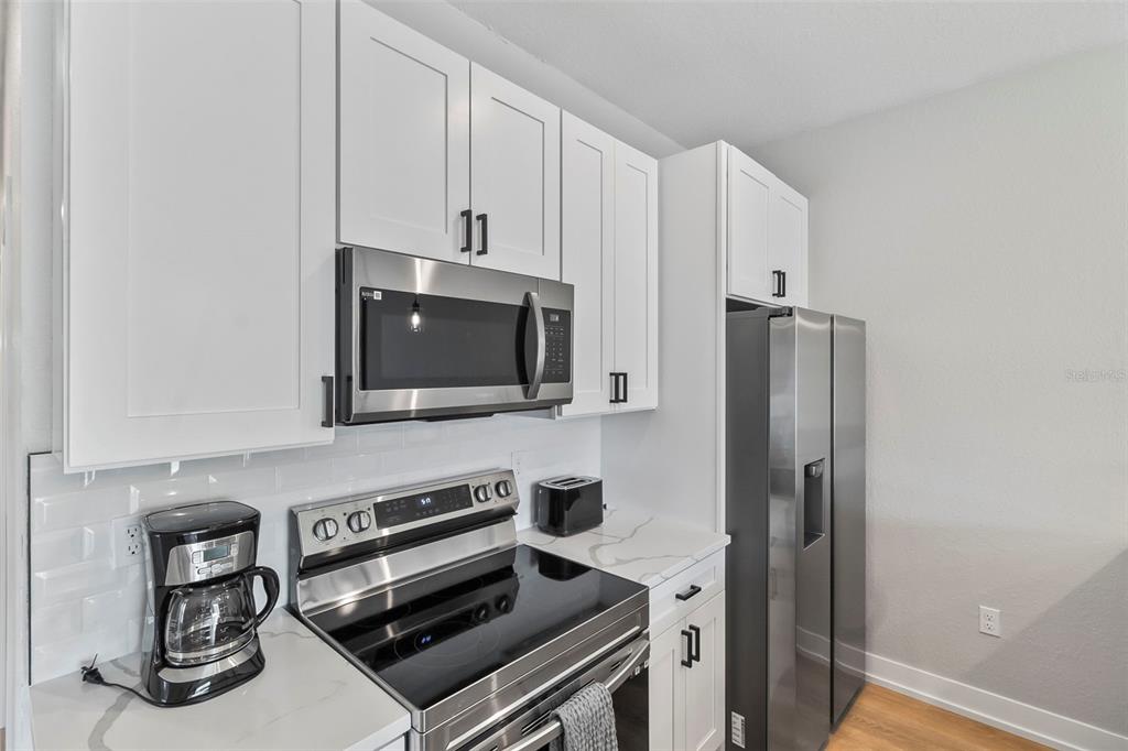 9155 Agate Street Port Charlotte, FL 33981 - Photo 25 of 30 a kitchen with stainless steel appliances a stove a microwave and a refrigerator