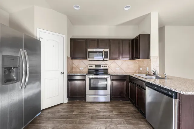 a kitchen with granite countertop stainless steel appliances and wooden cabinets