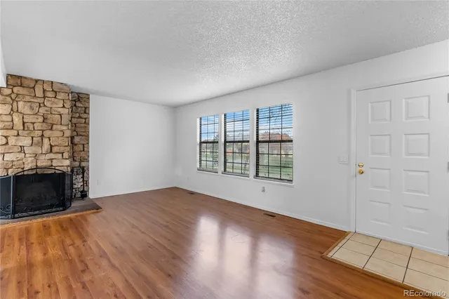 wooden floor fireplace and windows in an empty room