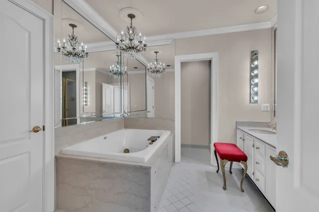 a bathroom with a bath tub a sink and a chandelier