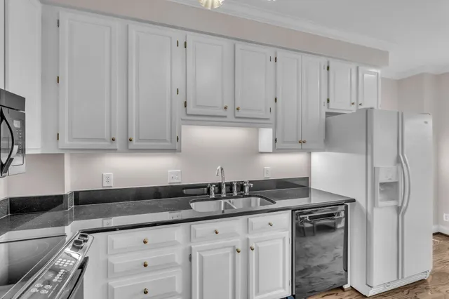 a kitchen with granite countertop white cabinets and stainless steel appliances