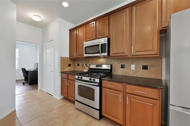 a kitchen with granite countertop wooden cabinets and stainless steel appliances