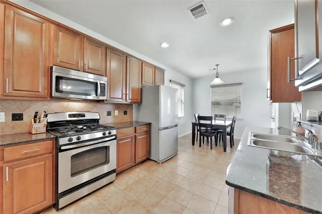 a kitchen with stainless steel appliances granite countertop a stove top oven a sink a dining table and chairs
