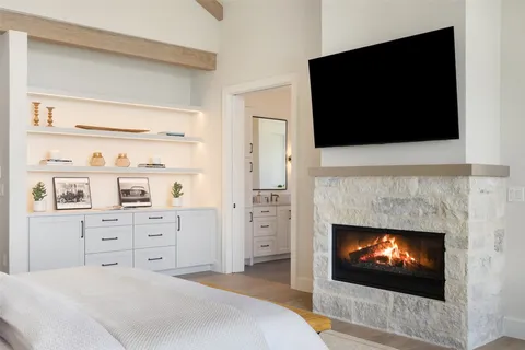 a spacious bedroom with a fireplace and a flat screen tv
