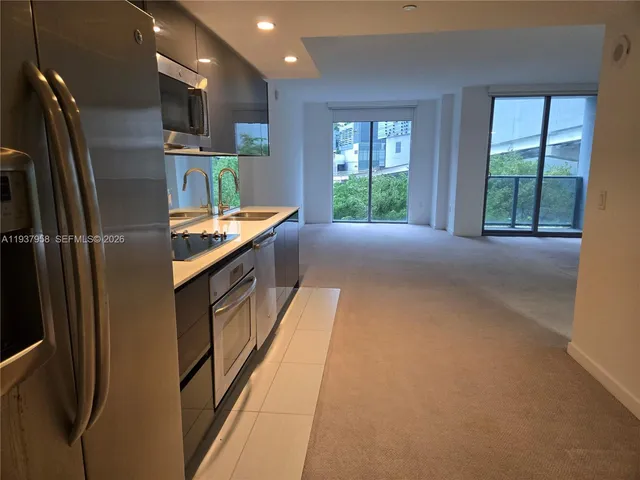 a kitchen with stainless steel appliances granite countertop a refrigerator a sink a stove and a refrigerator with windows