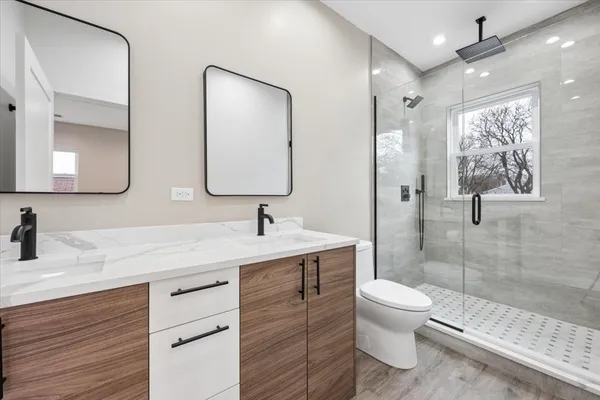 a bathroom with a toilet a sink a glass door a shower a mirror and vanity