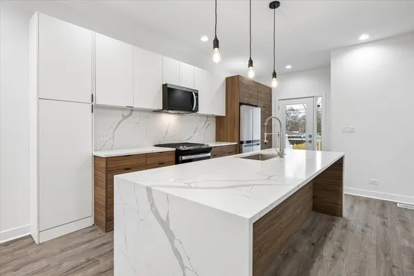 a kitchen with kitchen island a sink stainless steel appliances and wooden floor