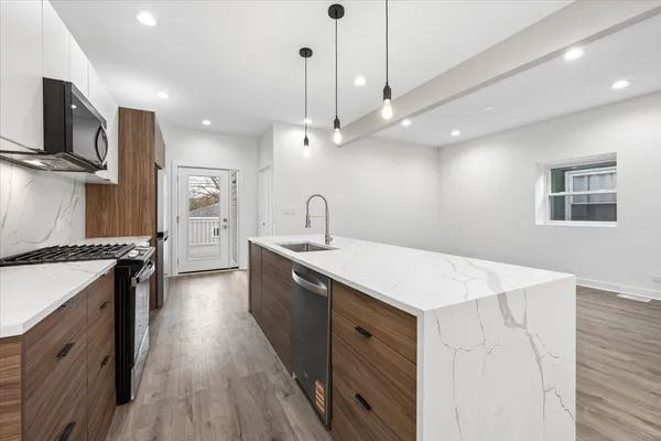 a kitchen with a sink stainless steel appliances and wooden floor