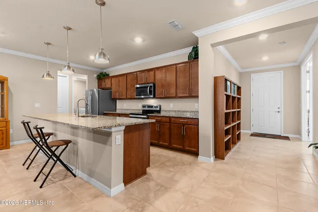 a kitchen with stainless steel appliances granite countertop a stove top oven a sink island and a refrigerator