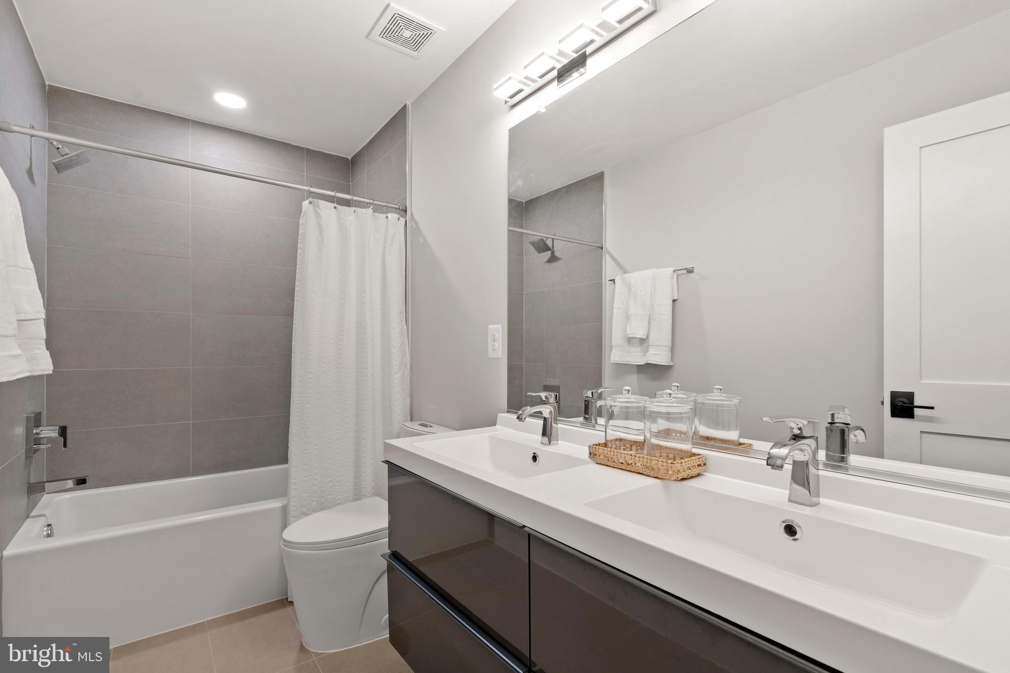 910 9th Street Northeast, Unit 1 Washington, DC 20002 - Photo 48 of 66 a bathroom with a double vanity sink toilet mirror and bathtub