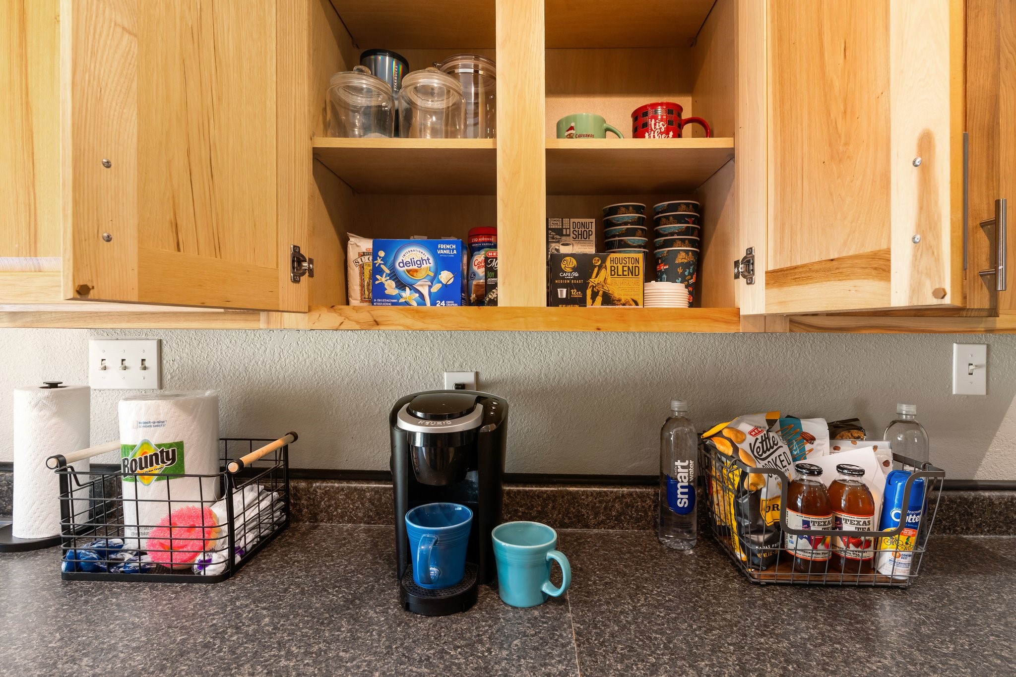 14758 Kirbee Drive Conroe, TX 77302 - Photo 7 of 35 This kitchen photo showcases a cozy coffee setup with a sleek countertop, wooden cabinets, a coffee maker, and ample storage space for mugs and supplies. Ideal for coffee enthusiasts.