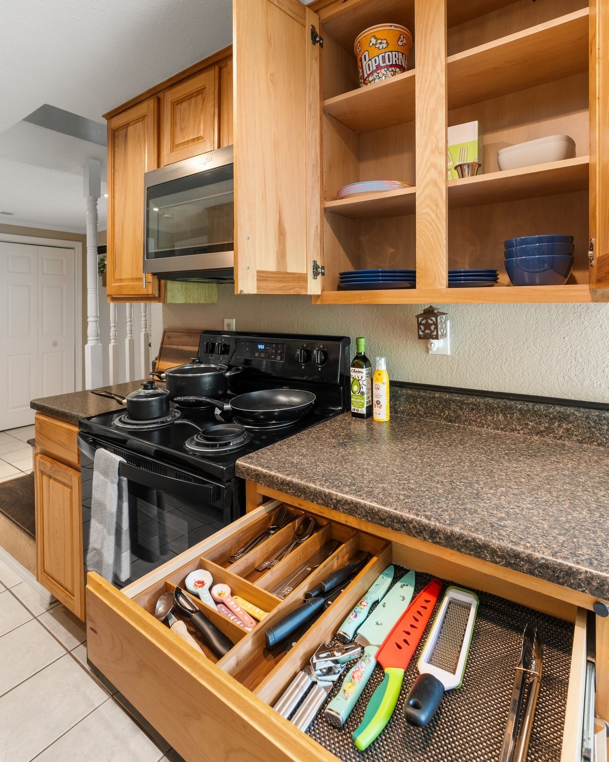 14758 Kirbee Drive Conroe, TX 77302 - Photo 8 of 35 This kitchen features warm wood cabinetry with ample storage, a sleek black stove, and a built-in microwave. It has a spacious countertop and organized drawers, perfect for a functional cooking space.