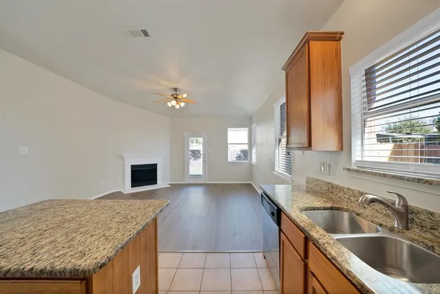 a kitchen with a sink dishwasher and fireplace with wooden floor