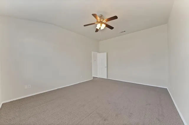 an empty room with a ceiling fan and a window
