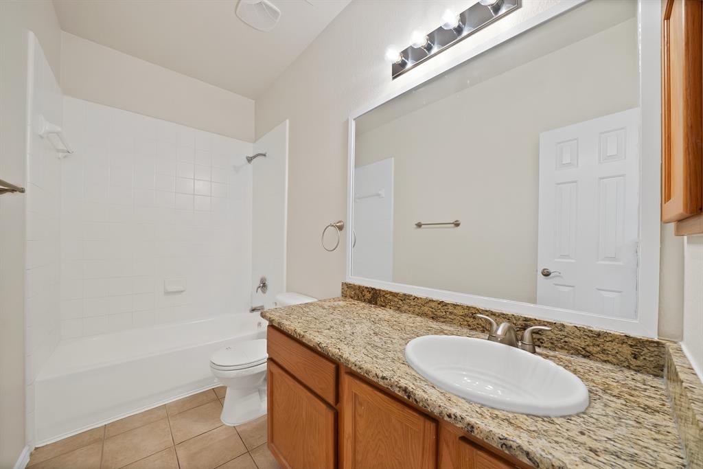 3813 Cane River Road Fort Worth, TX 76244 - Photo 24 of 28 a bathroom with a granite countertop sink a toilet a mirror and bathtub