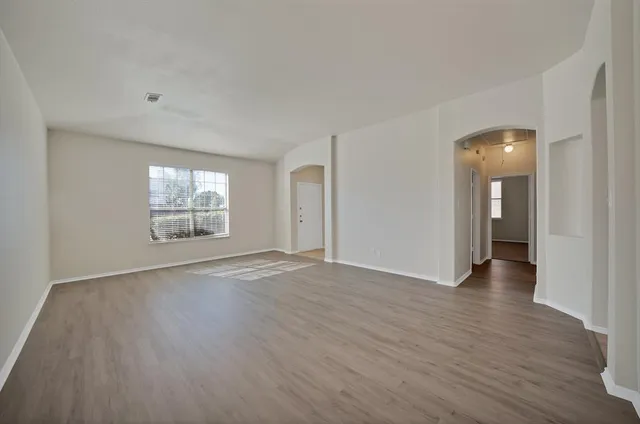 an empty room with wooden floor and windows