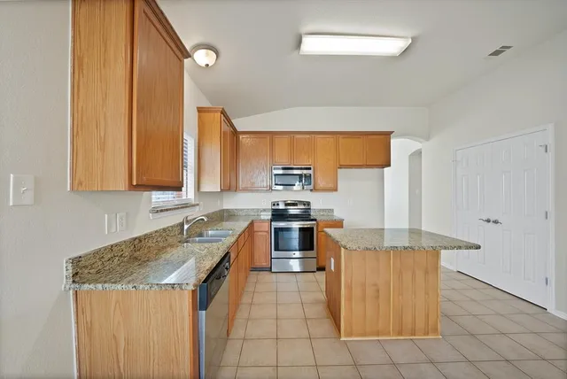 a kitchen with stainless steel appliances granite countertop a stove a sink dishwasher and a refrigerator