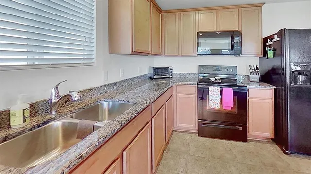 a kitchen with stainless steel appliances granite countertop a refrigerator sink stove microwave and cabinets