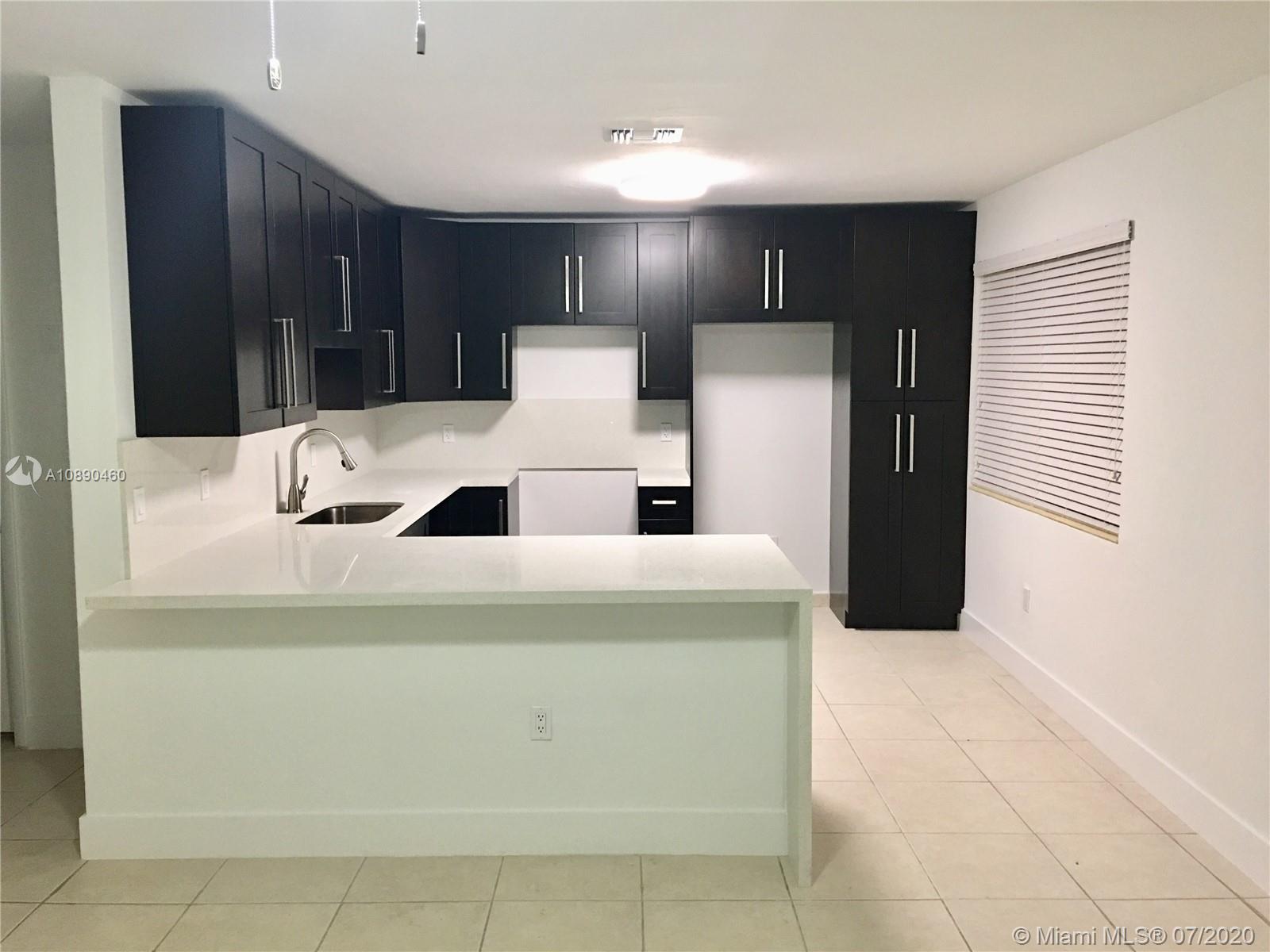 310 Southwest 34th Avenue, Unit 310 Miami, FL 33135 - Photo 7 of 18 a kitchen with kitchen island cabinets and refrigerator