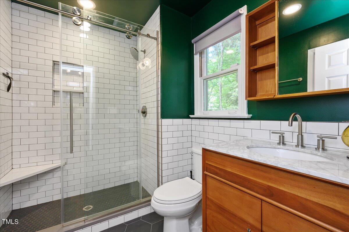2005 Broadingham Court Raleigh, NC 27615 - Photo 17 of 27 a bathroom with a granite countertop toilet a sink a mirror and shower