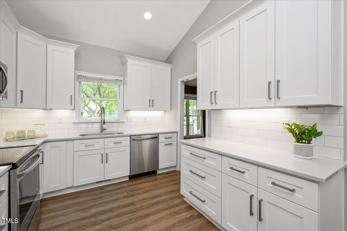 2005 Broadingham Court Raleigh, NC 27615 - Photo 7 of 27 a kitchen with white cabinets white appliances sink and wooden floor