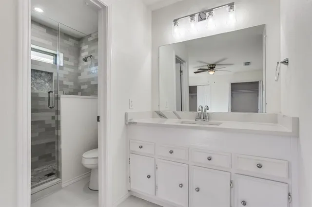 a bathroom with a granite countertop sink mirror and toilet