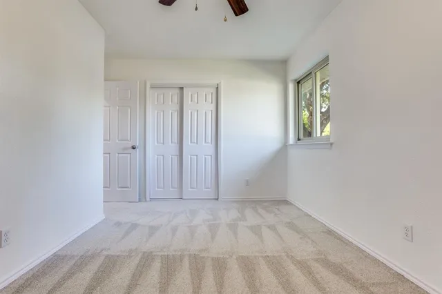 a view of an empty room with window and closet area
